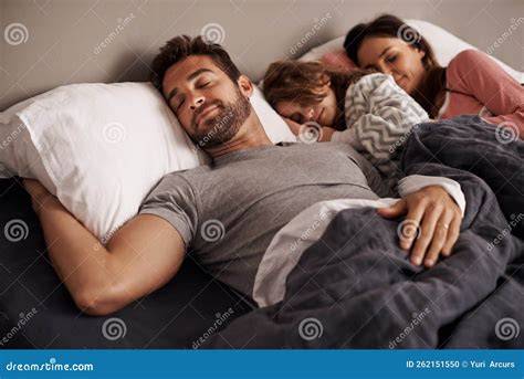 Bebé durmiendo plácidamente junto a sus padres en una cama familiar