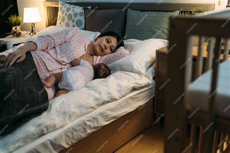 Madre amamantando a su bebé en la cama durante la noche, resaltando el vínculo
