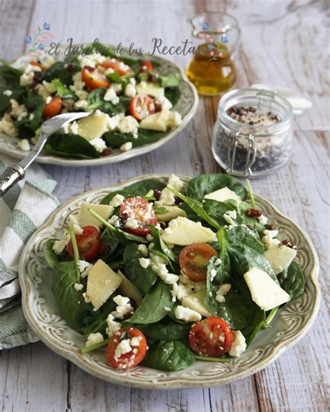 Ingredientes frescos para la ensalada: espinacas, tomates cherry, queso feta en bloque, nueces y aceitunas, dispuestos artísticamente.