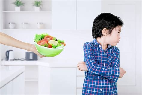 Ilustración de un niño pequeño rechazando un plato de comida, con padres preocupados en el fondo