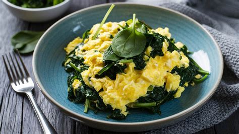 Fotografía de un plato de huevos revueltos bien cocidos con espinacas, ejemplificando un desayuno seguro y nutritivo para el embarazo