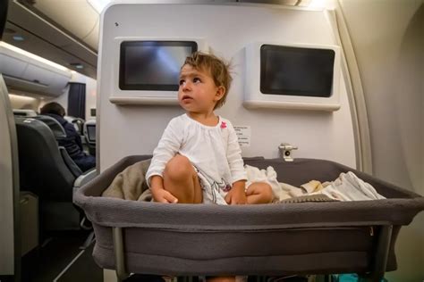 Bebé durmiendo cómodamente en una cuna de avión, con padres atentos