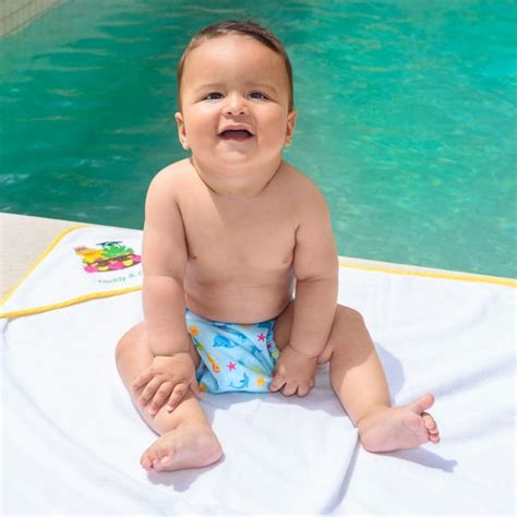 Bebé sonriente con un pañal de natación de colores vivos en una piscina