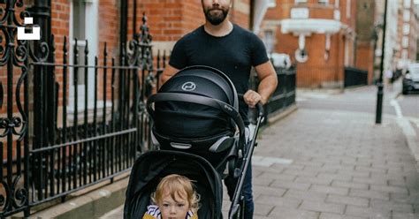 Un niño empujando un cochecito de bebé equipado con un bolso de silla Tuc Tuc de diseño divertido