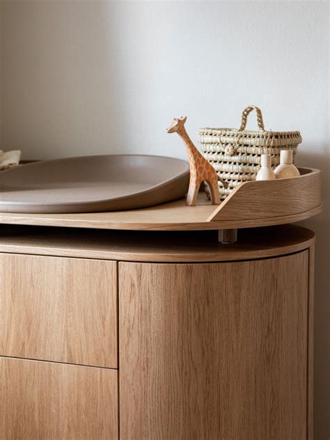 Foto detallada de un cambiador de madera con bordes elevados y organizador lateral de accesorios.