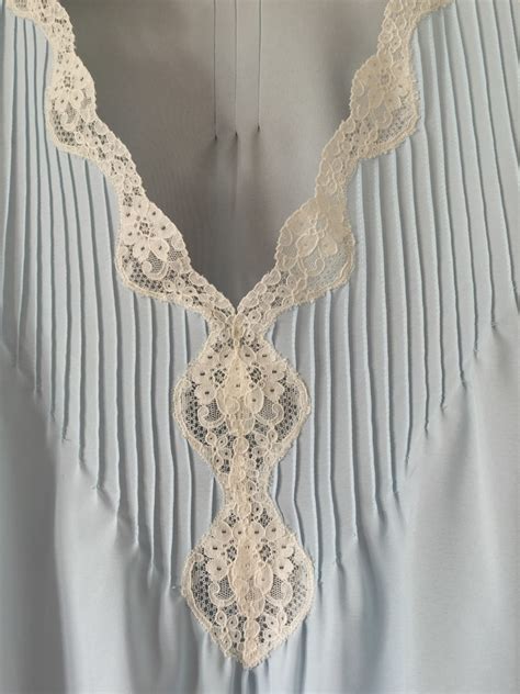 Detalle de encaje en el escote y tirantes finos de un camisón de seda para lactancia