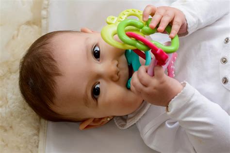 Bebé mordiendo un collar de lactancia de silicona para aliviar el dolor de encías.