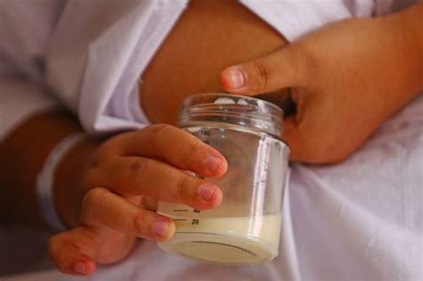 Foto de una madre aplicando leche materna en el pezón de forma segura.