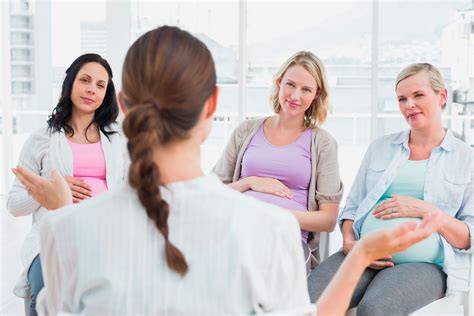 Mujer embarazada asistiendo a un taller grupal con otras futuras madres y una matrona
