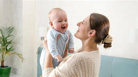 Bebé de 3 semanas sonriendo mientras lo sostiene un adulto