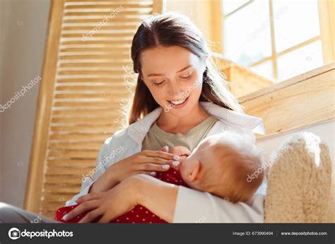 Madre amamantando a su bebé en una bandolera de anillas con un fondo suave