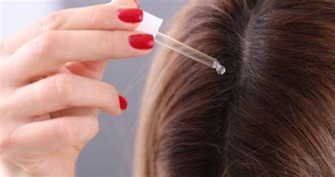 mujer aplicando una ampolla de placenta en su cabello, con énfasis en el cuero cabelludo