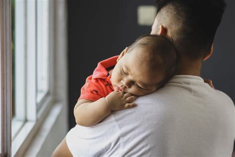 Foto de un bebé cómodo sobre el hombro de su padre, eructando