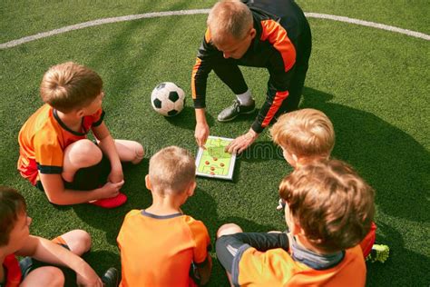 Entrenador de fútbol explicando ejercicio a un grupo de niños