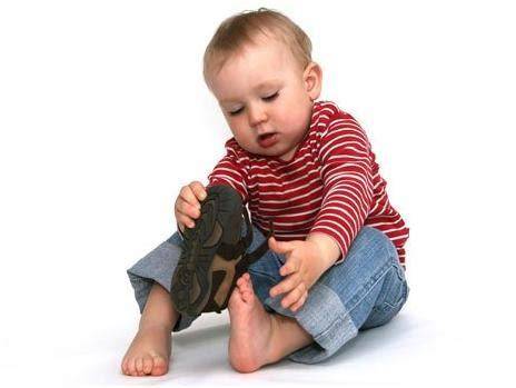 Foto de un niño pequeño intentando ponerse los zapatos