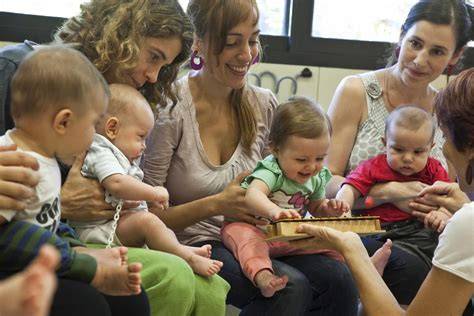 Foto de grupo de madres con bebés en un taller de lactancia presencial, compartiendo experiencias