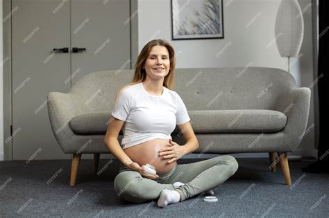 Foto de una mujer embarazada sonriente aplicando crema en su vientre