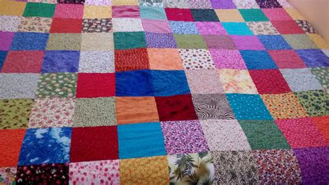 Primer plano de la textura de una colcha patchwork, mostrando la combinación de algodones y linos.