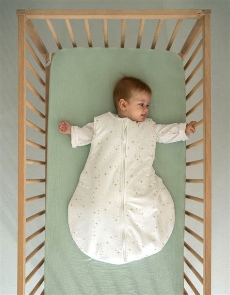 Foto de cuna vestida con textiles de algodón orgánico y saco de dormir
