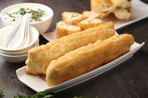 Infografía comparativa entre el Youtiao chino y el churro español, destacando diferencias en forma, sabor y método de elaboración.