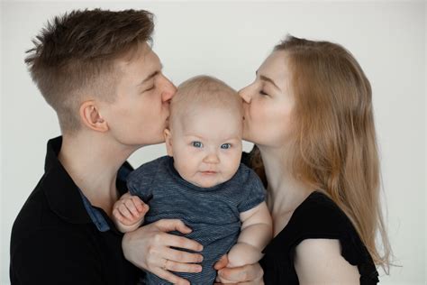 Bebé siendo sostenido en posición vertical después de una toma, con padres sonriendo.