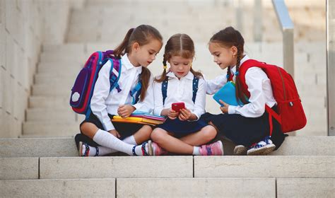Fotografía temática: Menores utilizando dispositivos móviles en un entorno escolar.