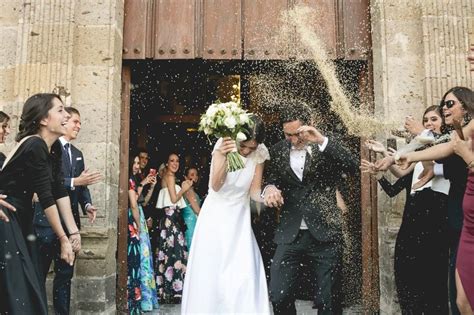 Foto de invitados lanzando arroz y pétalos a una pareja recién casada
