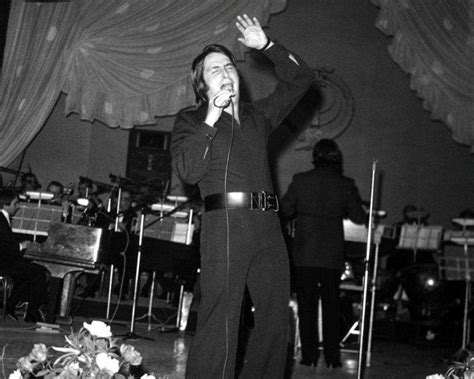 Fotografía de Nino Bravo en un concierto, con el micrófono en la mano y gesto expresivo.