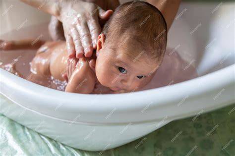 Padre bañando a su bebé recién nacido en una bañera pequeña