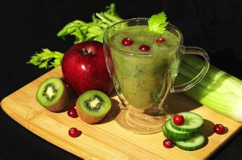 Batido verde fresco en un vaso con ingredientes alrededor