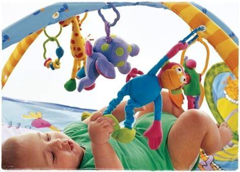 Bebé jugando felizmente en una manta de actividades colorida con juguetes colgantes