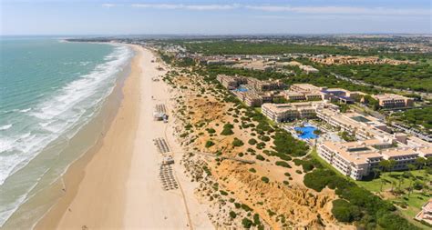 Foto aérea de la playa de La Barrosa al atardecer, con chiringuitos iluminados