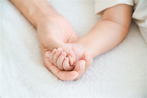 Foto de una madre de luto sosteniendo la mano de su bebé