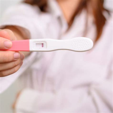 Mujer pensativa observando un test de embarazo negativo