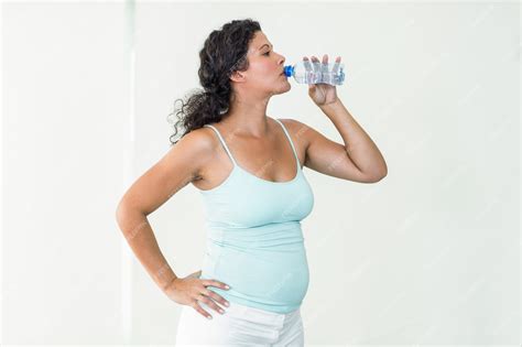 Foto de mujer embarazada bebiendo agua, enfatizando la hidratación
