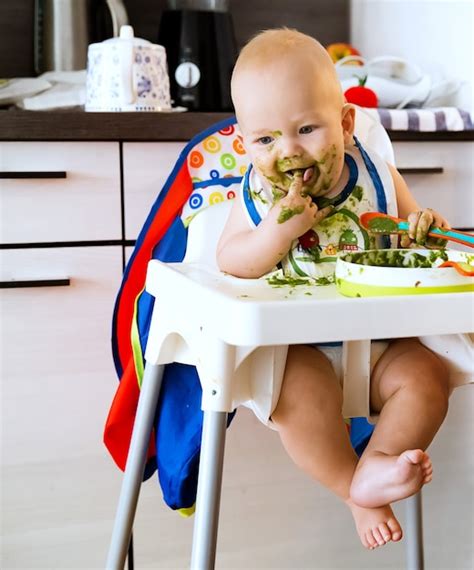 Bebé comiendo cereales con cuchara en silla alta