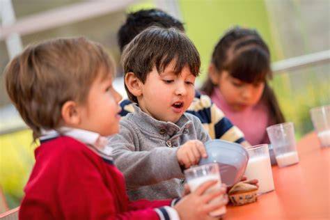 Foto de niños pequeños interactuando con alimentos de forma divertida y educativa