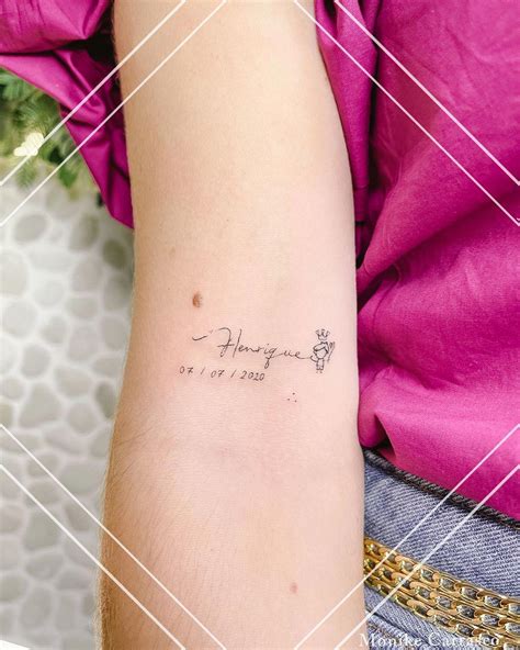 Tatuaje con el nombre de un hijo en caligrafía fina en el antebrazo