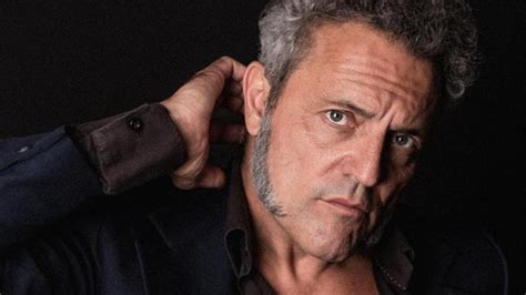 Retrato fotográfico de Carlos Tarque con estética de rock clásico, posiblemente en un entorno natural o de estudio con iluminación cálida