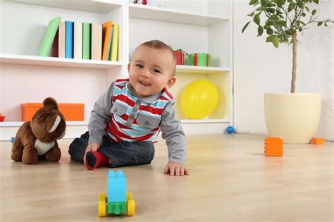 Bebé niña sonriendo y jugando, vestida con un pichi de color suave