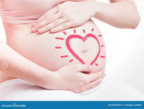 Fotografía de una mujer embarazada con las manos sobre su vientre, con una expresión de serenidad.