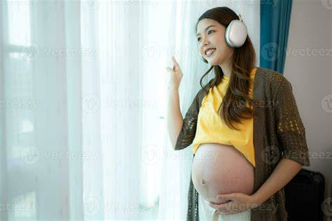 Madre embarazada relajándose mientras escucha música con auriculares en su vientre