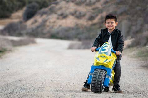 Niño pequeño montando una moto correpasillos, con una sonrisa en su rostro.