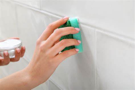 Limpieza de las juntas de los azulejos con una esponja húmeda para eliminar residuos.