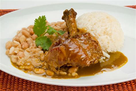 Plato de seco de cabrito servido con arroz blanco, frijoles y yuca sancochada