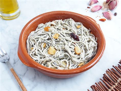 Fotografía de gulas al ajillo humeantes servidas en cazuela de barro con pan
