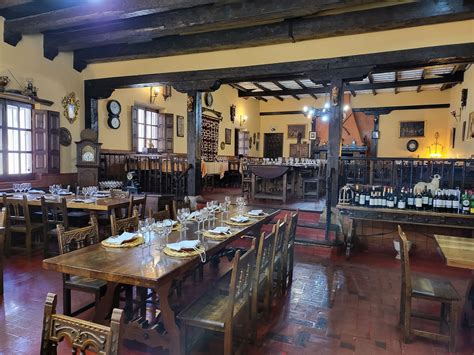 Fotografía del interior de un mesón castellano tradicional con decoración rústica y mesas de madera.