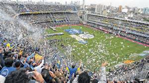 Fotografía de una tribuna de La Bombonera llena de hinchas con banderas y camisetas azul y oro
