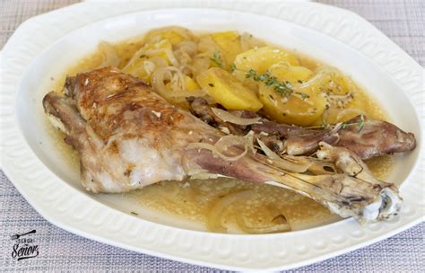 Plato de paletilla de cabrito al horno dorado y jugoso servido con guarnición de patatas panaderas y cebolla