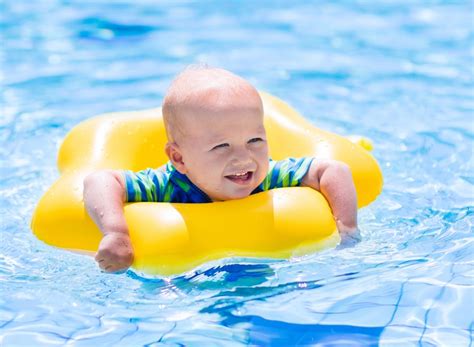 Bebé sonriendo y jugando con un flotador en el agua, con sus padres.